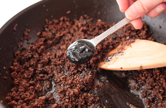 肉の色が変わったらAを混ぜて加え、水1カップを加える。強めの中火で7～8分煮詰めて、黒練りごま、黒すりごま、ナンプラー、こしょう、みじん切りのねぎを加えて混ぜる。