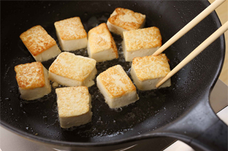 フライパンにごま油大さじ1を中火で熱し、豆腐をじっくり焼き、上下に焼き色がついたら取り出す。フライパンにごま油大さじ1をたし、にんにく、しょうがを中火で炒める。香りが出てきたら青梗菜の軸を加えてざっと炒める。油がなじんだらうなぎ、青梗菜の葉を加える。