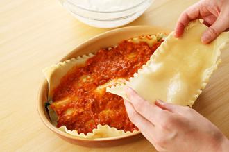 耐熱の器に、ミートソース、パスタ、ホワイトソース、ほうれん草の順に2回重ね、最後にミートソース、チーズをのせる。220度に予熱したオーブンで15～20分焼く。