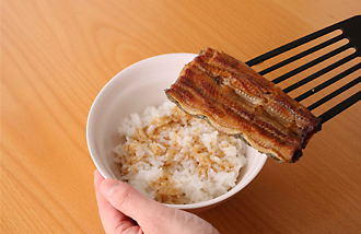 器にご飯を盛り、うなぎのたれをサッとかける。焼いたうなぎをのせ、万能ねぎ、三つ葉をのせておろしわさびを添える。