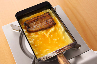 卵焼き器にサラダ油を塗って中火で熱し、卵液の1/3量を流し入れる。気泡を菜箸でつぶし、奥にうなぎのかば焼きをのせる。半熟状になったら、うなぎを手前に巻き込みながら卵を巻く。空いたところにペーパータオルでサラダ油を薄く塗り、巻いた卵を奥側に寄せる。この工程を、同様に2回繰り返す。熱いうちに巻きすで形をととのえ、粗熱がとれたら食べやすく切って皿に盛り、大根おろしを添える。