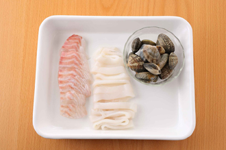 鯛は食べやすくそぎ切りにし、いかは幅1センチの輪切りにする。あさりはよく洗う。にんにくはつぶす。