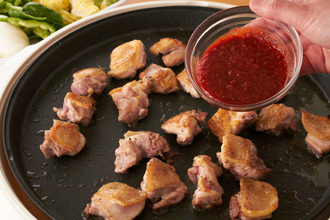 ホットプレートにごま油を熱し、鶏肉の皮を下にして並べ、全体がこんがりするまで焼きつける。タレを加えてサッと炒める。肉の上にさつまいも、キャベツ、玉ねぎ、キムチをのせてふたをして、ときどき混ぜながらさつまいもが柔らかくなるまで蒸し焼きにする（焦げつくようなら酒か水をたす）。仕上げにピーマンを加えて全体をあえる。
