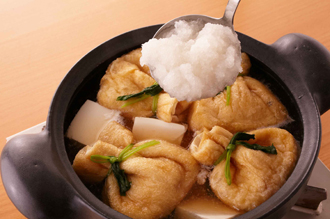 土鍋にAを入れて中火にかけ、煮立ったら豆腐、巾着を入れる。再び煮立ったら大根おろしを加えて三つ葉を散らし、温まったらでき上がり。
