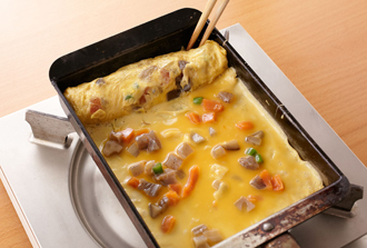 だし巻き卵を作る。煮しめは粗みじんに切る。ボウルに卵を溶きほぐし、Bと煮しめを加えて混ぜる。卵焼き器にサラダ油を薄く塗って中火で熱し、卵液の1/3量を流し入れる。気泡を菜箸でつぶし、半熟状になったら手前に折りたたむ。卵を向こう側に寄せ、手前に卵液の1/2量を入れて同様に焼き、それをもう1回繰り返す。熱いうちにペーパータオルで形をととのえ、粗熱がとれたら食べやすく切って皿に盛る。