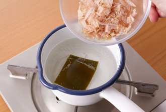 だしをとる。鍋に水と昆布を入れて中火にかけ、細かい泡が昆布のまわりについてきたらかつお節を加える。火を止めて、かつお節が底に沈んだらざるでこす。