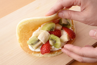 パンケーキに具をのせる。いちごはへたを取って縦4等分に切り、バナナ、キウイも1.5センチ角くらいの食べやすい大きさに切る。パンケーキにチーズクリームとフルーツの1/4量をのせ、パンケーキを折りたたんで包む。