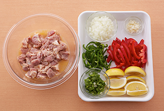 豚肉は2センチ角に切ってボウルに入れ、Aを加えてもみ込み、15分以上おく。玉ねぎ、にんにくはみじん切りにする。ピーマン、パプリカは縦半分に切って種を取り、横に幅5ミリに切る。香菜はざく切りにする。レモンはくし形切りにする。