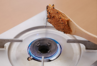 木べらにみそを塗りつけ、コンロの直火であぶって表面に焦げ目をつける。