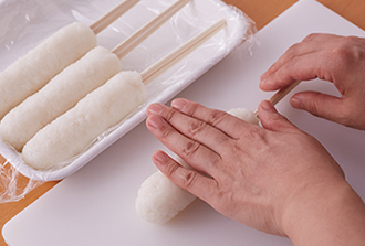 ご飯をすり鉢（またはボウル）に入れ、すりこ木（またはめん棒）で7割くらいまでつぶす。4等分にして、塩水（分量外）をつけた手で丸め、割り箸（割らずに1膳のまま）にさして細長くまとめる。まな板の上で転がし、形をととのえる。