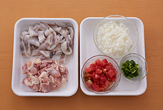 いかは内臓と軟骨を抜いて洗い、胴は輪切りにし、足も食べやすい大きさに切る。鶏肉は小さめの一口大に切る。玉ねぎはみじん切りにする。トマトは1cm角、ピーマンは1cm四方に切る。