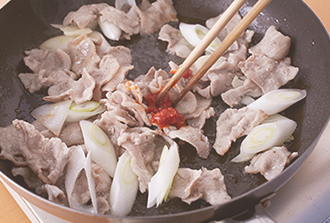 肉の端が白くなってきたら上下を返し、にんにく、ねぎを加えてさっと混ぜ、豆板醤も加えて香りを出す。