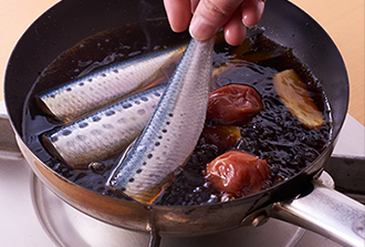 フライパンに梅干し、しょうが、Aを入れて強めの中火にかける。煮立ったらいわしを並べ入れ、切り込みを入れたオーブン用シートなどをのせて落としぶたにし、10分ほど煮る。