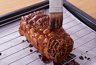 天板にオーブン用シートを敷いて焼き網をのせ、豚肉をのせる（漬け汁は取っておく）。200度に予熱したオーブンで10分ほど焼き、上下を返し、刷毛で肉の漬け汁を塗る。再びオーブンに入れ、これを4回ほどくり返す（焼き時間は約40分）。