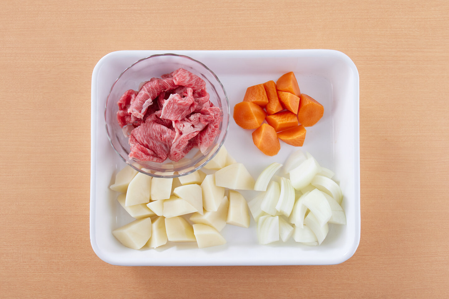 じゃがいもは皮をむいて食べやすい大きさに切り、サッと水にさらしてから水けをきる。玉ねぎは幅1センチのくし形切りにし、長さを半分に切る。にんじんは皮をむいて一口大の乱切りにする。牛肉は大きいものは食べやすい長さに切る。