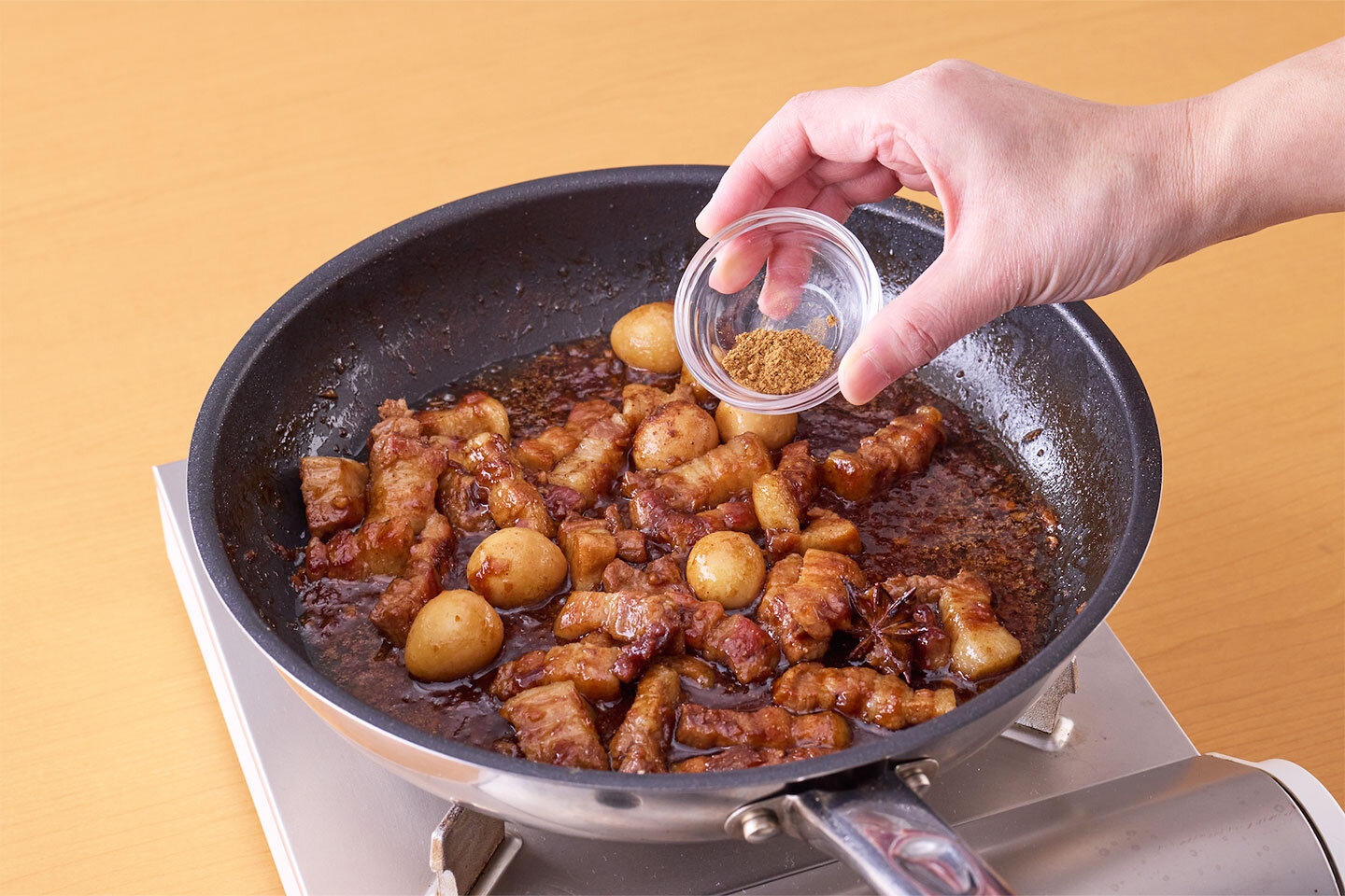 五香粉を加えて混ぜ、さらに5分ほど煮る。<br>器にご飯を盛って具をかけ、つけ合わせの高菜漬け、パクチー(香菜)を添える。